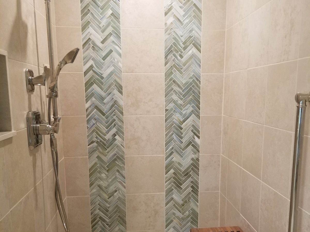 Finished shower with herringbone glass tile accent and teak bench