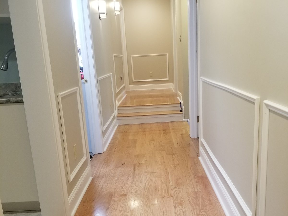 Finished hallway with hardwood flooring and wainscoting
