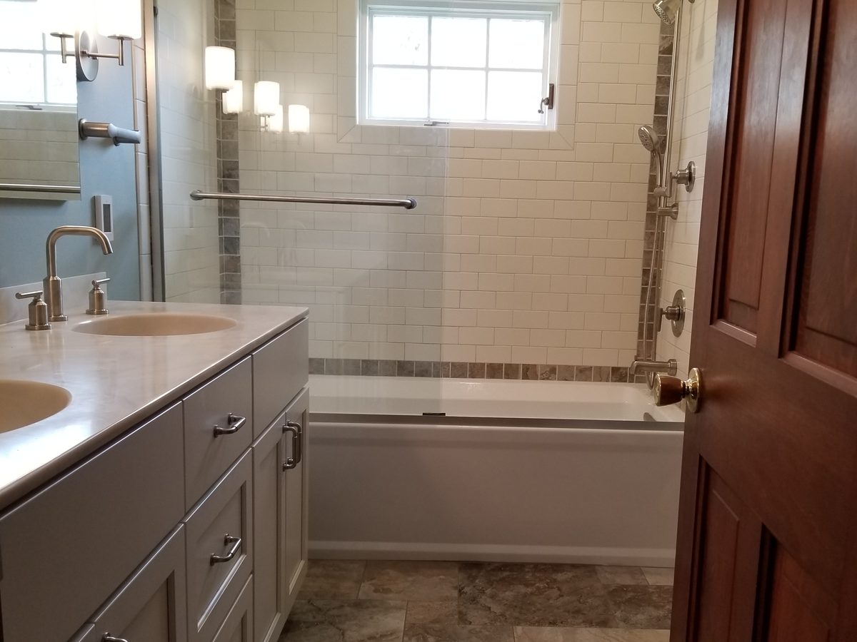 Subway tile tub surround with a stone accent band and a double vanity