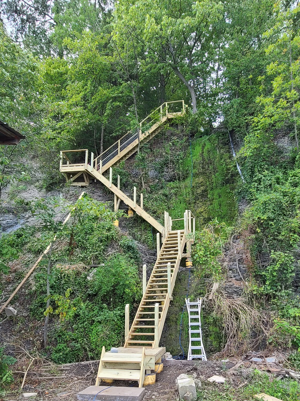 Multi flight pressure treated staircase running down a wooded ravine in the Finger Lakes region