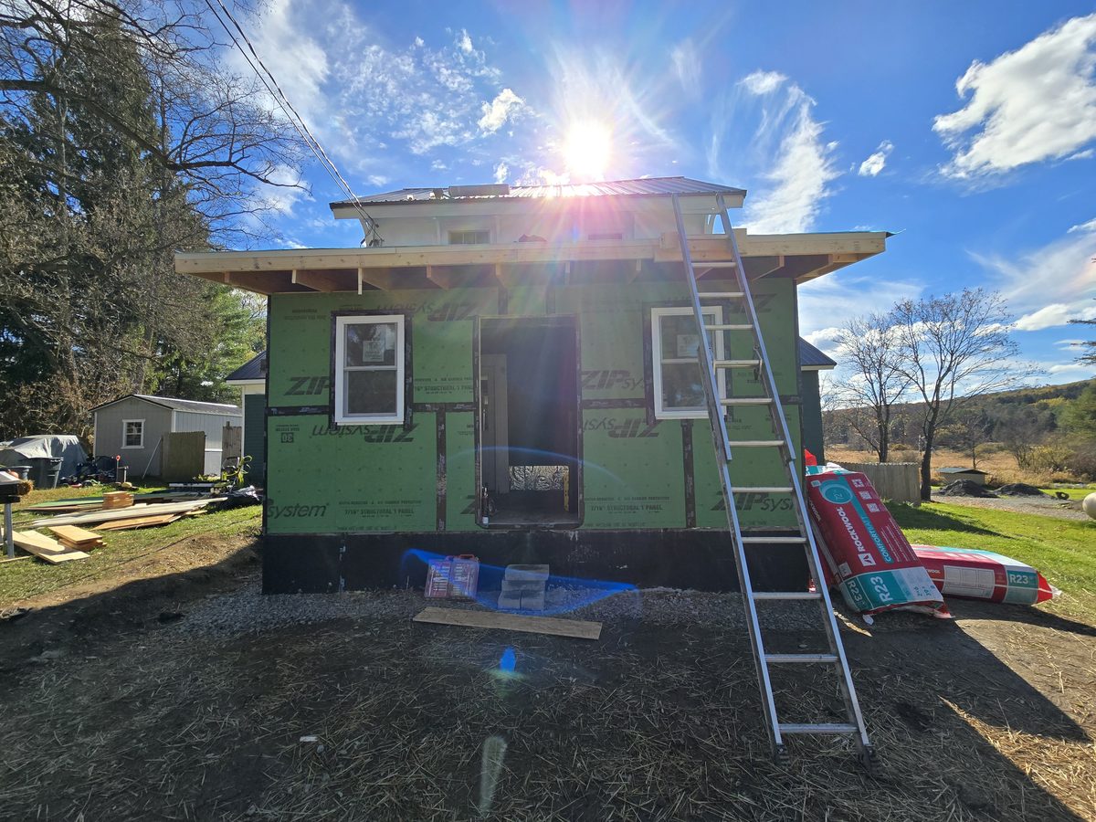 Home addition under construction, wrapped in weather barrier with new framing