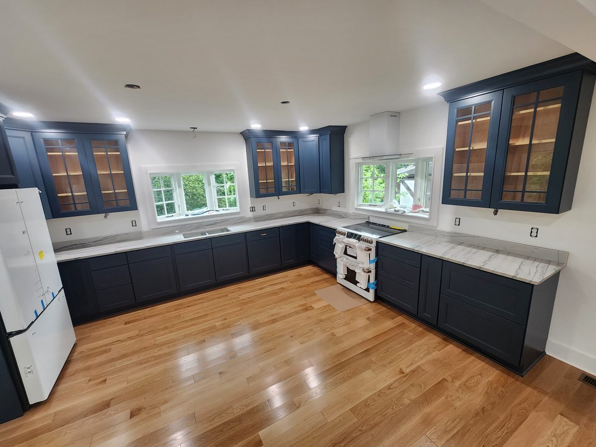 Finished kitchen remodel with navy cabinetry and marble countertops
