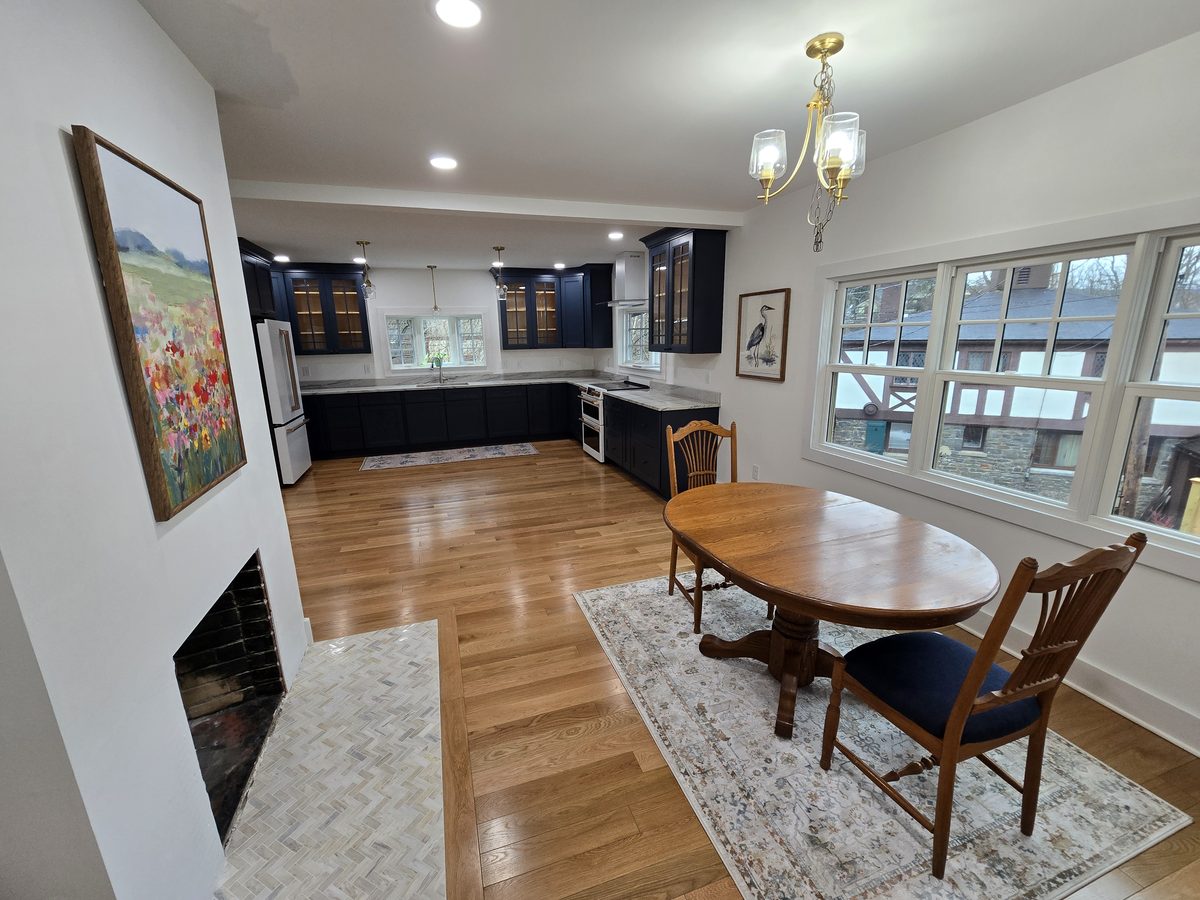 Finished kitchen remodel in the Finger Lakes region, with navy cabinetry, marble countertops, and refinished hardwood floors
