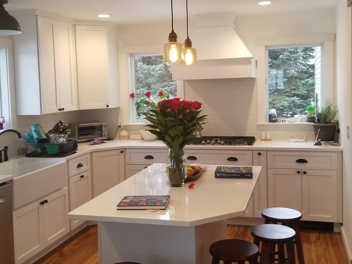 Finished white shaker kitchen with island and fresh roses