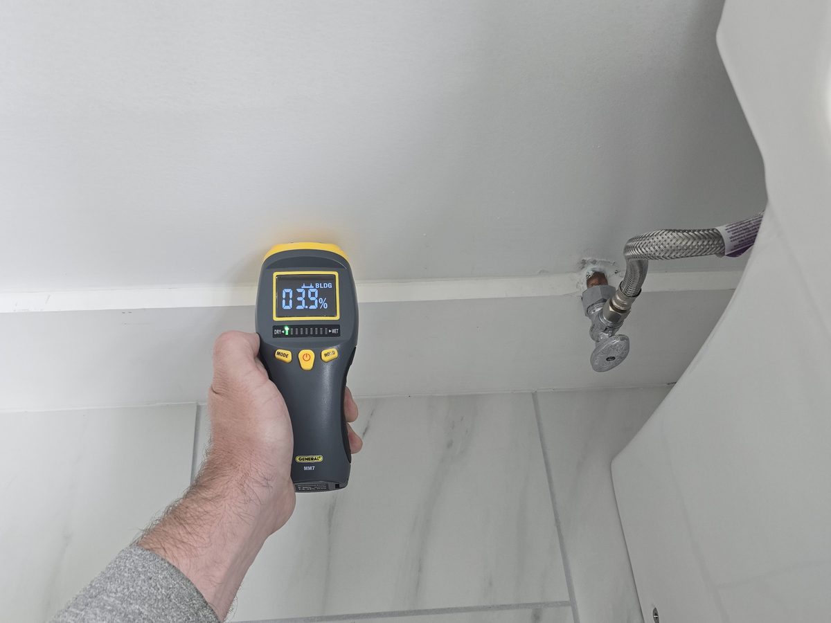 Moisture meter reading a wall beside a supply line